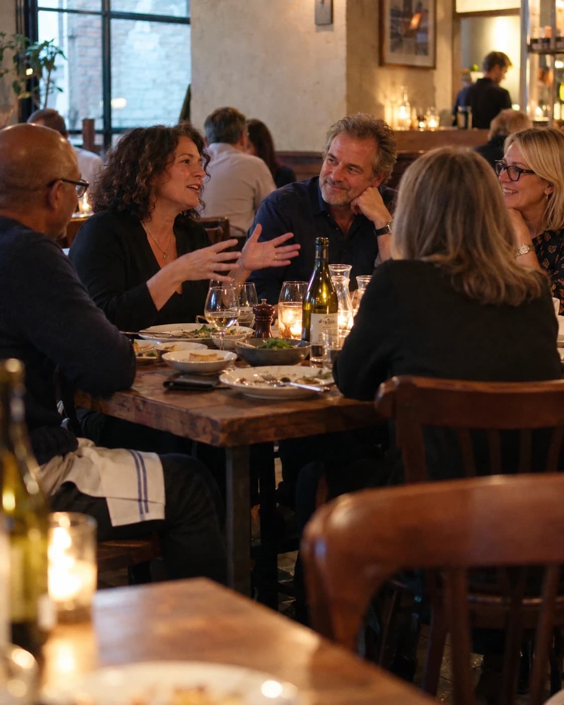 A matched group talking over dinner at a candlelit restaurant table