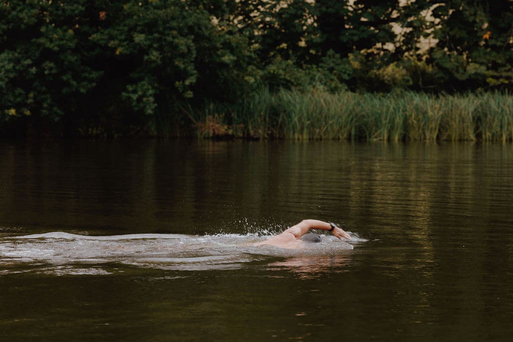 A wild swimmer crossing the lake at 42 Acres, Somerset