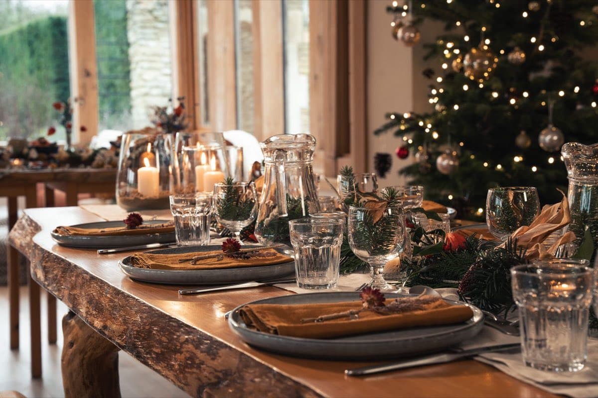 A candlelit festive table laid for dinner beside the Christmas tree