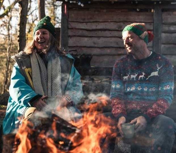 Two people laughing by a fire